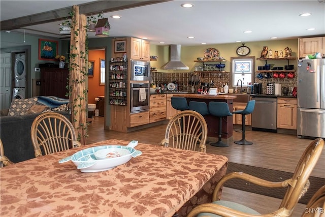 dining space featuring stacked washer and clothes dryer, dark hardwood / wood-style floors, and wet bar