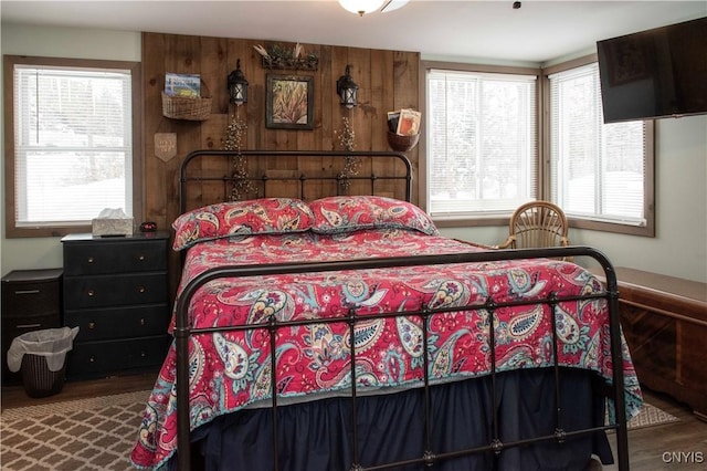 bedroom with multiple windows, hardwood / wood-style floors, and wooden walls