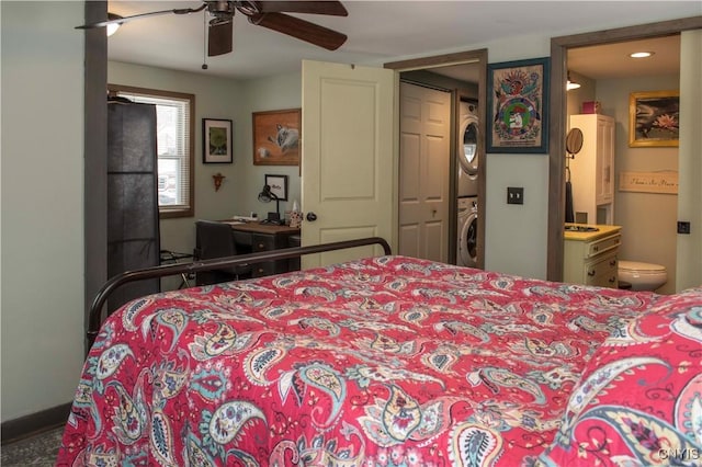 bedroom featuring ensuite bathroom, ceiling fan, and stacked washer / dryer