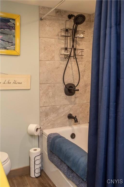 bathroom featuring shower / bathtub combination with curtain, hardwood / wood-style flooring, and toilet