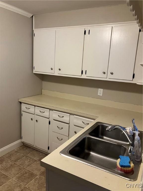 kitchen featuring white cabinetry, sink, ornamental molding, and dark tile patterned flooring