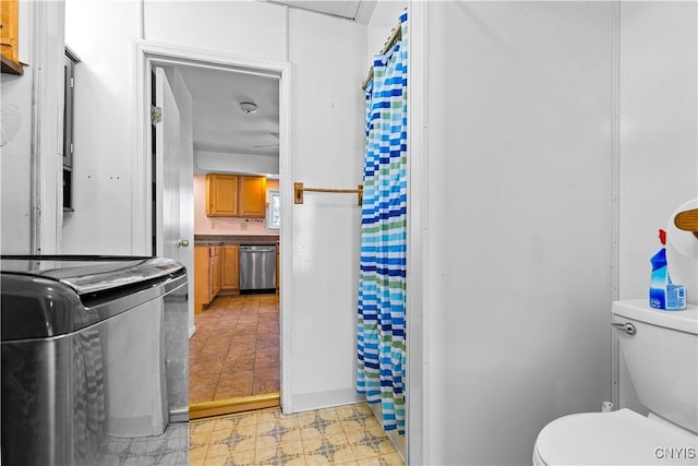 bathroom with washer / clothes dryer, a shower with shower curtain, and toilet