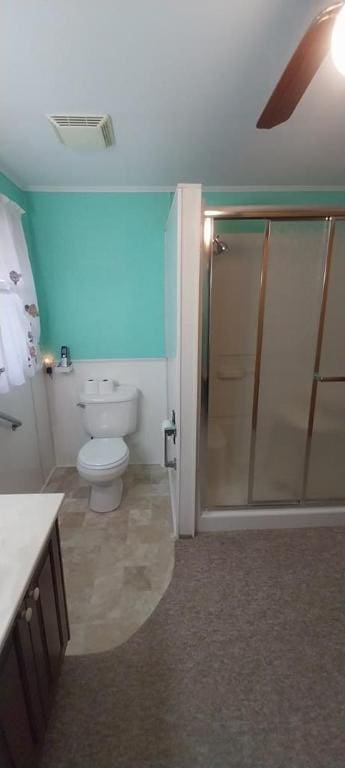 bathroom with a shower with door, vanity, ceiling fan, and toilet