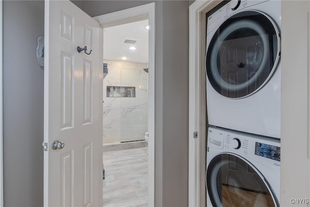 laundry room featuring light hardwood / wood-style flooring and stacked washer and clothes dryer