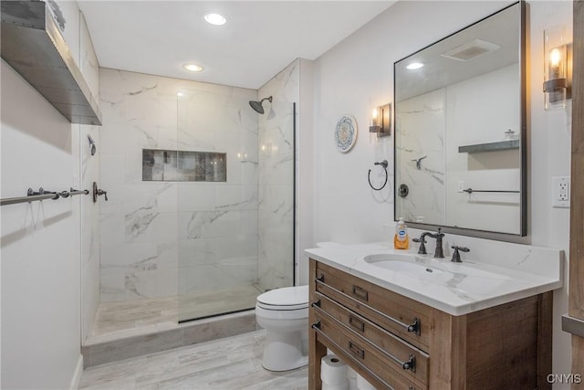 bathroom featuring vanity, a tile shower, and toilet