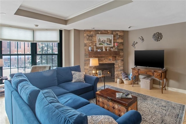 living room with a tray ceiling, a stone fireplace, ornamental molding, and wood-type flooring