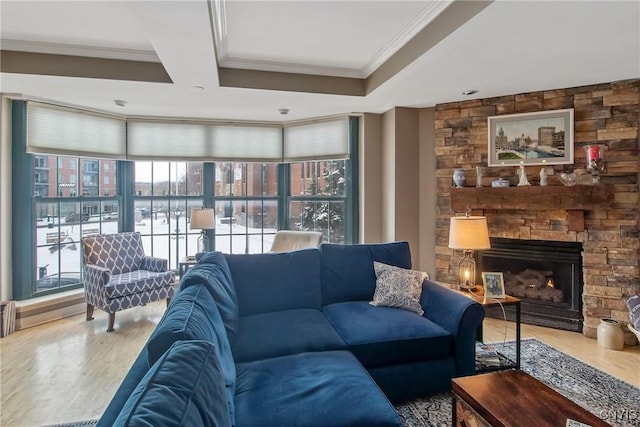 living room with hardwood / wood-style flooring, ornamental molding, and a stone fireplace