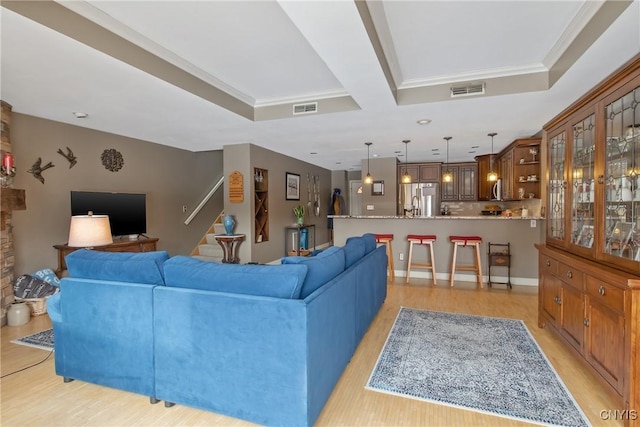 living room with crown molding, a tray ceiling, and light hardwood / wood-style floors