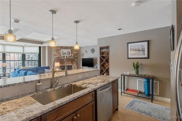 kitchen featuring hanging light fixtures, appliances with stainless steel finishes, sink, and light wood-type flooring