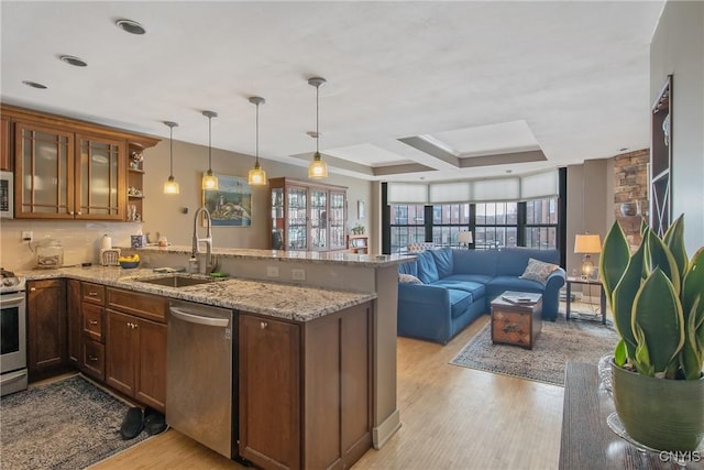 kitchen featuring hanging light fixtures, light stone countertops, appliances with stainless steel finishes, and kitchen peninsula