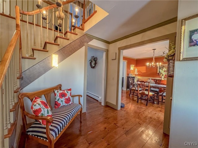 stairs featuring baseboard heating, wood-type flooring, crown molding, and a chandelier