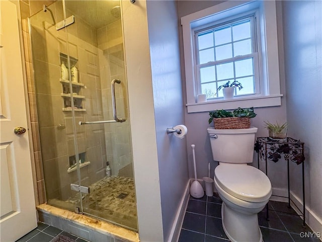 bathroom featuring tile patterned flooring, a shower with shower door, and toilet