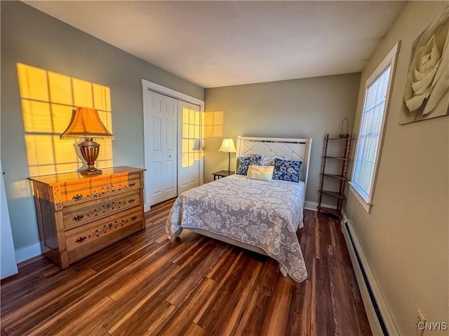 bedroom featuring dark hardwood / wood-style floors, a closet, and a baseboard heating unit