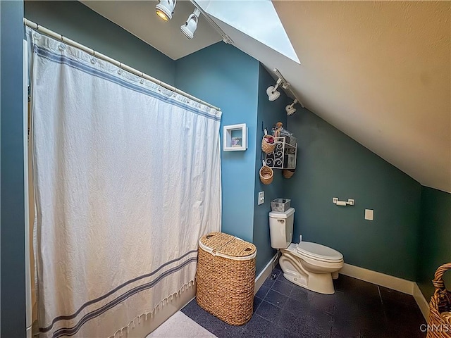 bathroom featuring vaulted ceiling with skylight and toilet