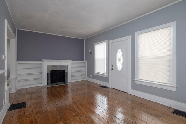 foyer featuring a premium fireplace, ornamental molding, and hardwood / wood-style floors