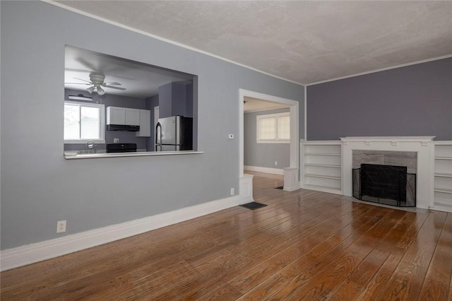 unfurnished living room with a fireplace, crown molding, wood-type flooring, and ceiling fan