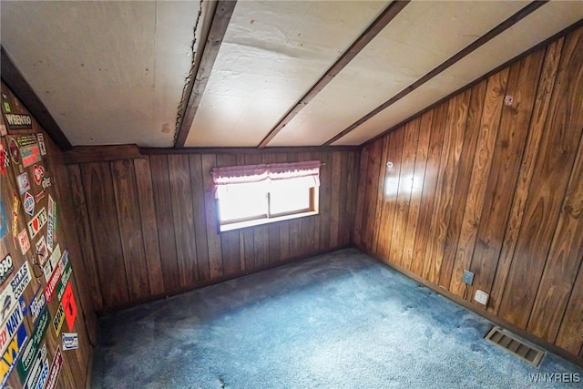 carpeted spare room featuring beamed ceiling and wood walls