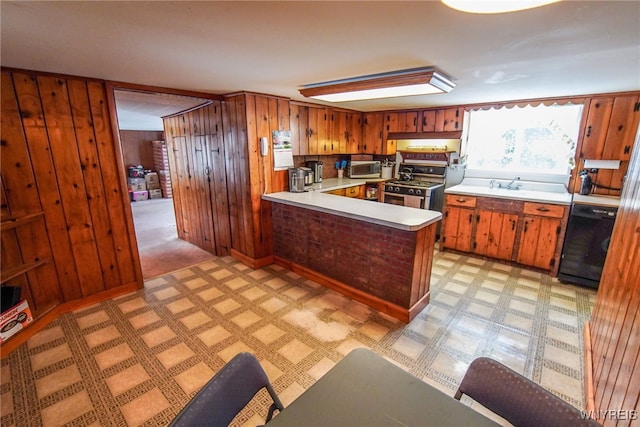 kitchen with wood walls, black dishwasher, sink, kitchen peninsula, and stainless steel gas range