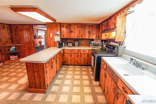 kitchen featuring backsplash, sink, wood walls, and appliances with stainless steel finishes