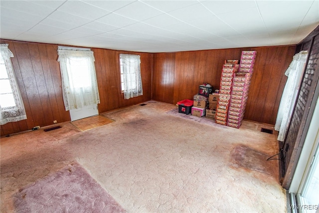 interior space with light carpet and wood walls