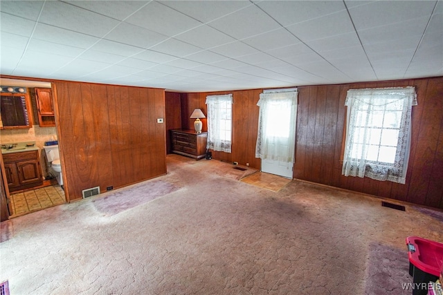 unfurnished living room featuring wooden walls and carpet