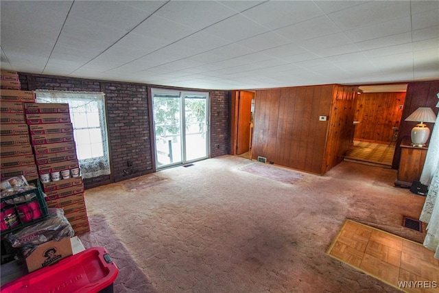 living room featuring brick wall, carpet floors, and wooden walls