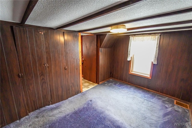 bonus room with light colored carpet, beam ceiling, a textured ceiling, and wood walls