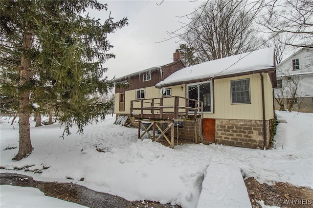 snow covered rear of property featuring a deck