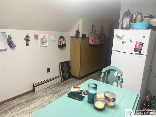 dining space featuring wood-type flooring, lofted ceiling, and a baseboard heating unit