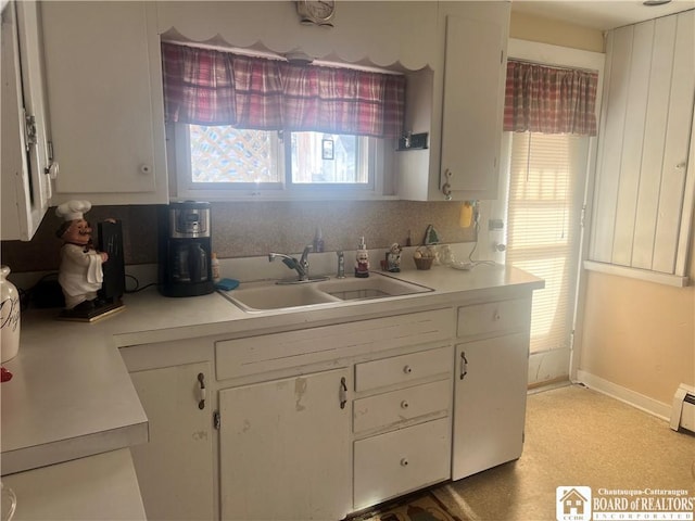 kitchen with sink, white cabinets, and backsplash