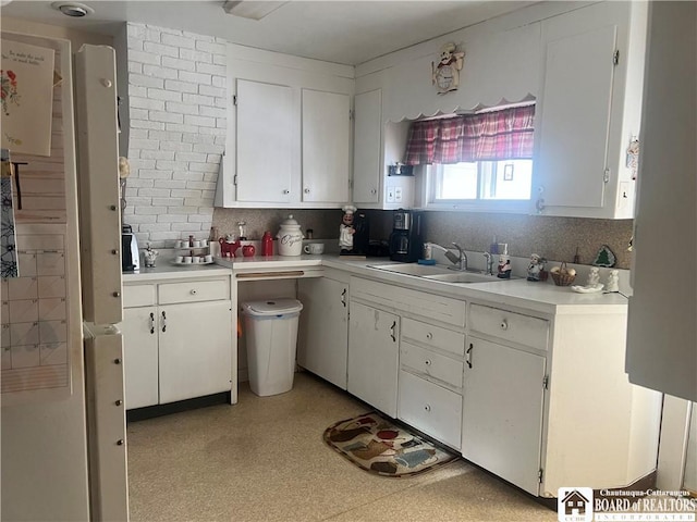 kitchen featuring tasteful backsplash, sink, and white cabinets