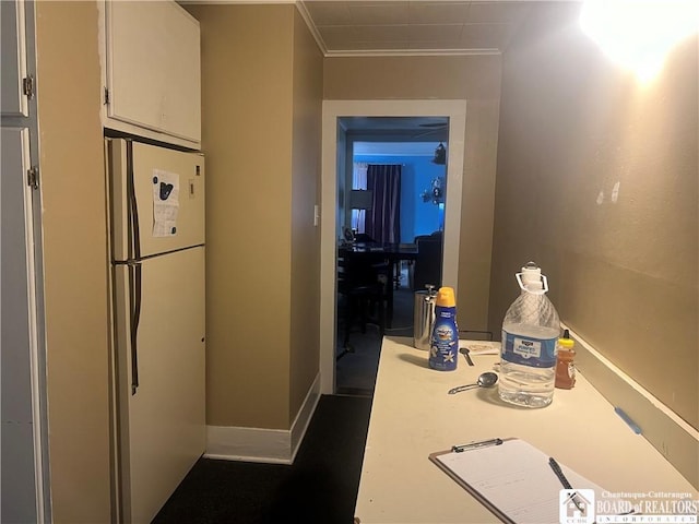 interior space featuring white refrigerator, white cabinetry, and ornamental molding