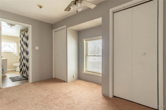 unfurnished bedroom with ceiling fan, light colored carpet, ensuite bath, and a closet