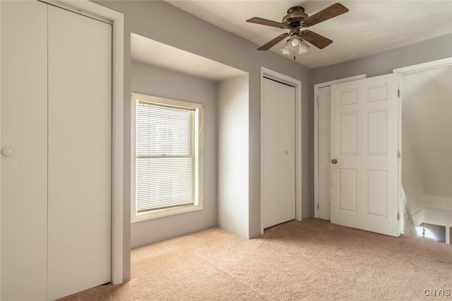 unfurnished bedroom featuring light colored carpet and two closets