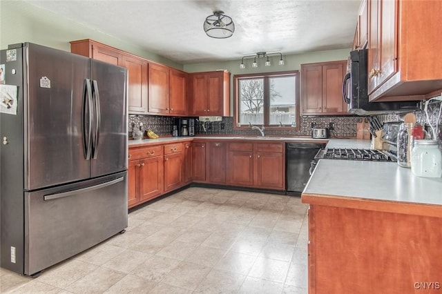 kitchen featuring stainless steel refrigerator, dishwasher, sink, backsplash, and range