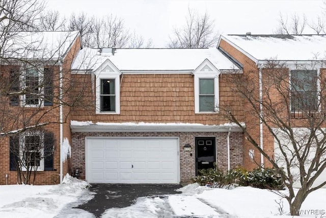 townhome / multi-family property with an attached garage, mansard roof, and brick siding