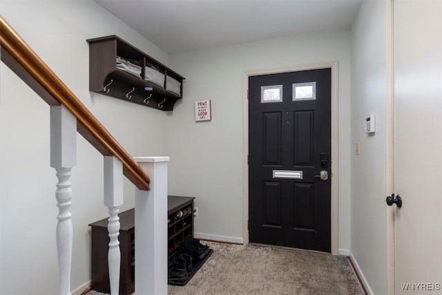 carpeted foyer entrance featuring baseboards and stairway