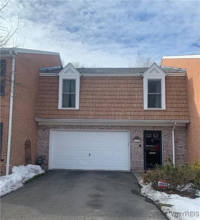 view of front of home with driveway, an attached garage, and brick siding