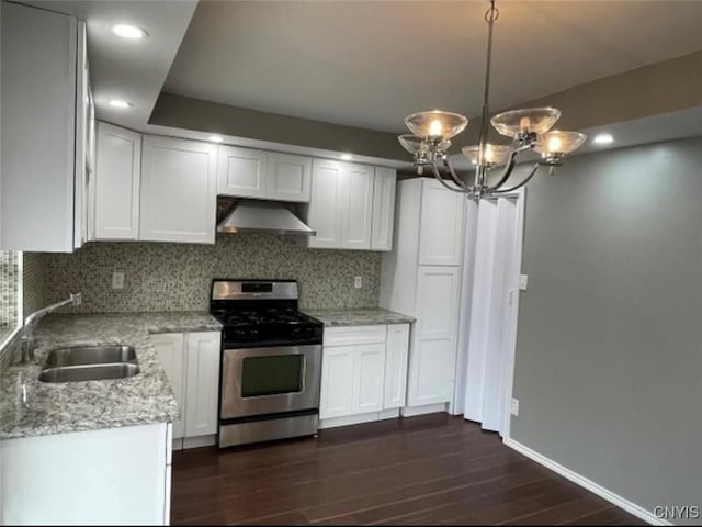 kitchen featuring pendant lighting, sink, white cabinets, stainless steel gas range, and wall chimney exhaust hood