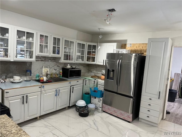 kitchen with white cabinetry, appliances with stainless steel finishes, sink, and backsplash