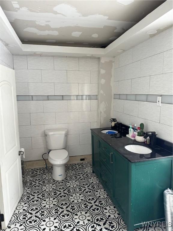 bathroom featuring tile walls, vanity, tile patterned floors, and toilet