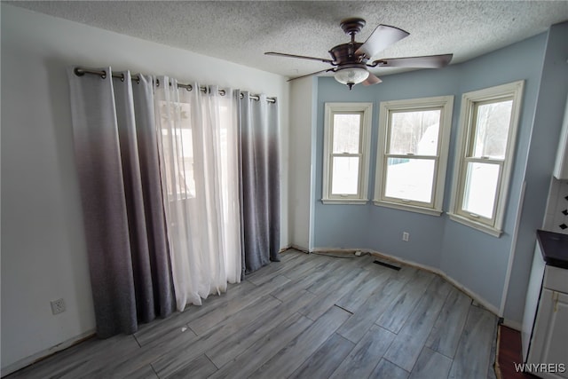 empty room featuring ceiling fan, a textured ceiling, and light wood-type flooring