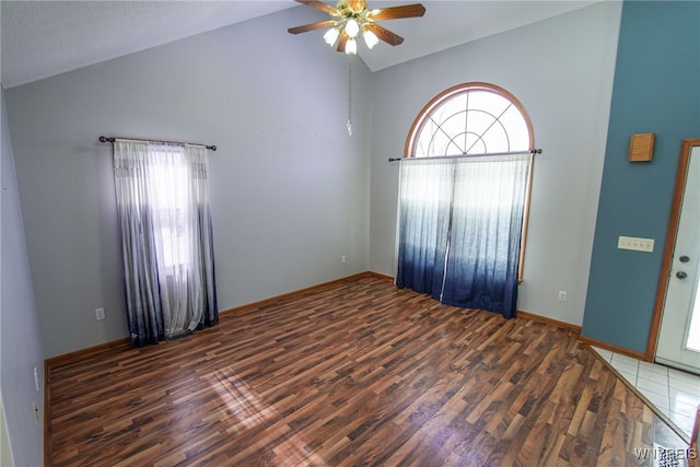 unfurnished room featuring vaulted ceiling, plenty of natural light, ceiling fan, and dark hardwood / wood-style flooring