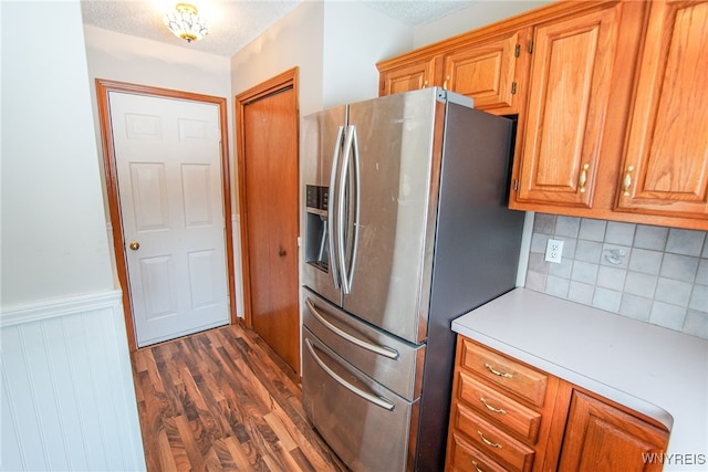 kitchen featuring stainless steel refrigerator with ice dispenser, decorative backsplash, dark wood-type flooring, and a textured ceiling