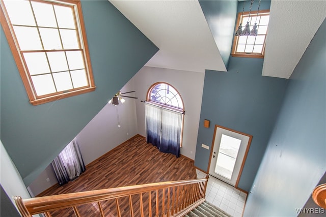 staircase featuring high vaulted ceiling, hardwood / wood-style floors, and ceiling fan