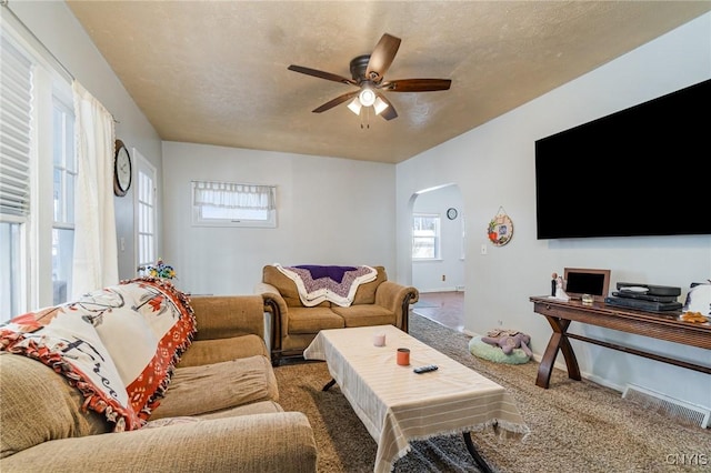 carpeted living room with ceiling fan and a textured ceiling