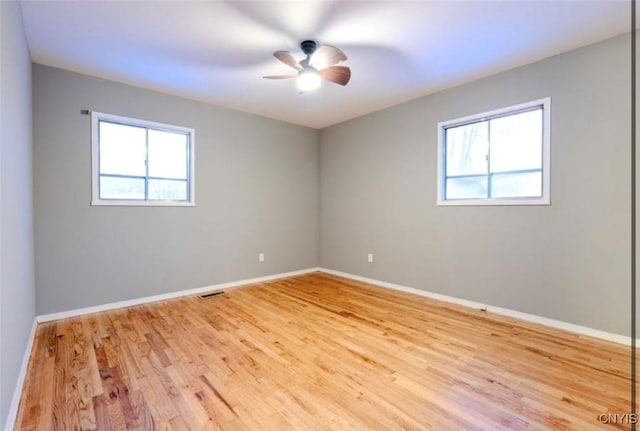 empty room with visible vents, plenty of natural light, light wood-style flooring, and baseboards