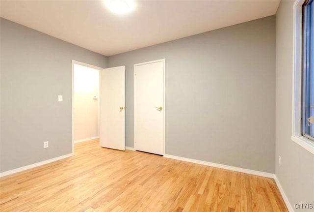 empty room featuring baseboards and light wood finished floors