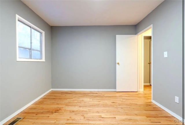 empty room featuring light wood-type flooring, visible vents, and baseboards