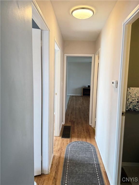 corridor featuring light wood finished floors, visible vents, and baseboards